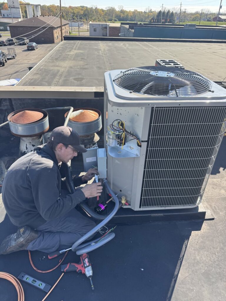 An HVAC technician installing a new rooftop air conditioning unit for Advantage Plumbing Heating & Air in Vandalia, OH.