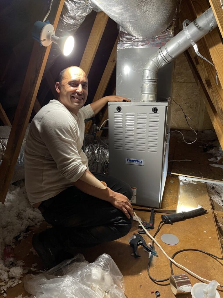 An HVAC technician from KMC Heating and Cooling LLC installing a Tempstar furnace in an attic in Clarksville, TN.