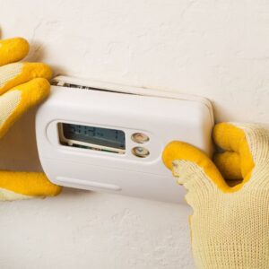 An HVAC technician installing or adjusting a thermostat for Cosmic HVAC in Chicago, IL.