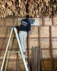An HVAC technician from Pappy's Heating & Air INC installing a thermostat or control panel in Clayton, NC.