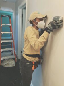 An HVAC technician installing a new thermostat on a wall at a client's property for Relief Heating and Cooling, LLC in Greensboro, NC.