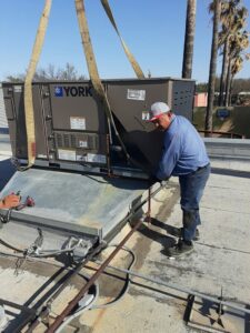An HVAC technician installing a large York unit on a rooftop for Norway Air Conditioning Inc. in Laredo, TX.