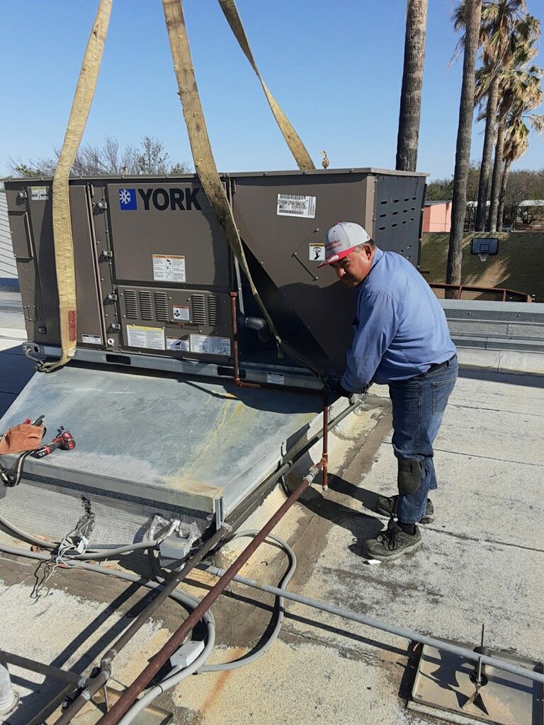An HVAC technician installing a large York unit on a rooftop for Norway Air Conditioning Inc. in Laredo, TX.