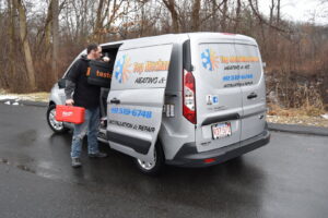 An HVAC technician loading tools into a branded service van for Top Mechanical Service in East Longmeadow, MA.