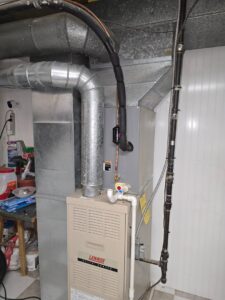 An HVAC technician performing maintenance on an outdoor air conditioning unit with tools for 24/7 Heating & Air, LLC in Grand Island, NE.