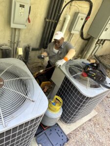 An Icy Hot Heating and Air Conditioning technician maintaining outdoor AC units in Raleigh, NC.