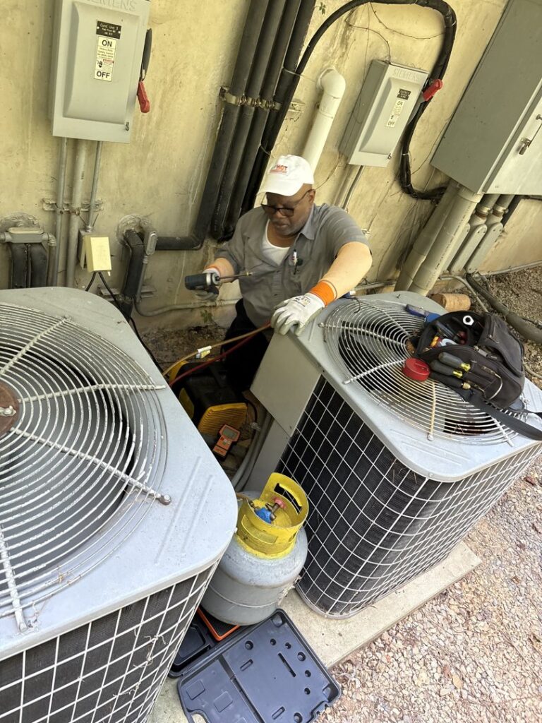 An Icy Hot Heating and Air Conditioning technician maintaining outdoor AC units in Raleigh, NC.