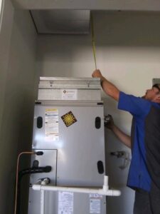 An HVAC technician measuring above a furnace unit during an installation or service by Element Heating & Cooling, Inc. in Twin Falls, ID