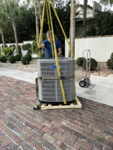 An Air Zero HVAC technician carefully moving a new outdoor AC unit with straps in Largo, FL