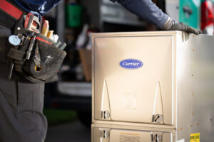 An HVAC technician with a tool belt next to a new Carrier furnace or air handler installation by Alan Energy Services in Naperville, IL