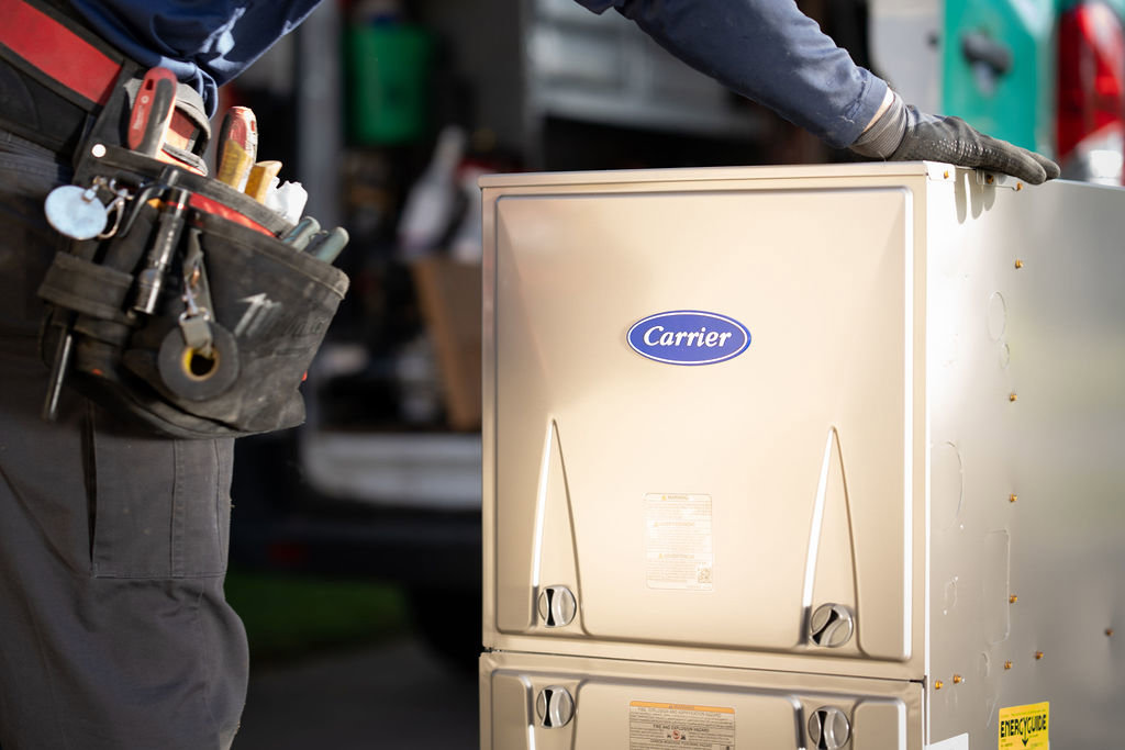 An HVAC technician with a tool belt next to a new Carrier furnace or air handler installation by Alan Energy Services in Naperville, IL