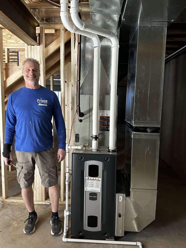 An HVAC technician from Friess Heating & Air Conditioning next to a new furnace installation in Topeka, KS
