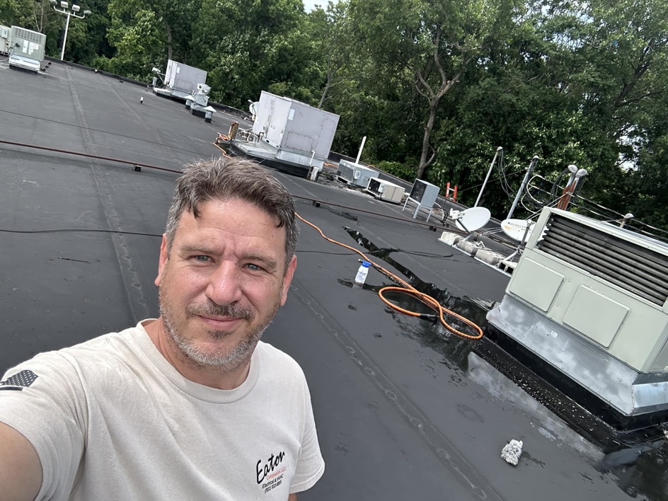 An HVAC technician on a commercial rooftop with multiple HVAC units for Eaton Companies LLC in Clarksville, TN.