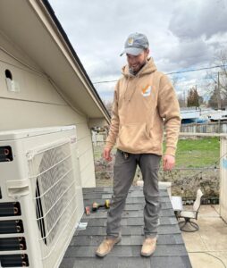 An HVAC technician on a roof next to a mini-split outdoor unit for Boise Valley Heating & Air in Meridian, ID