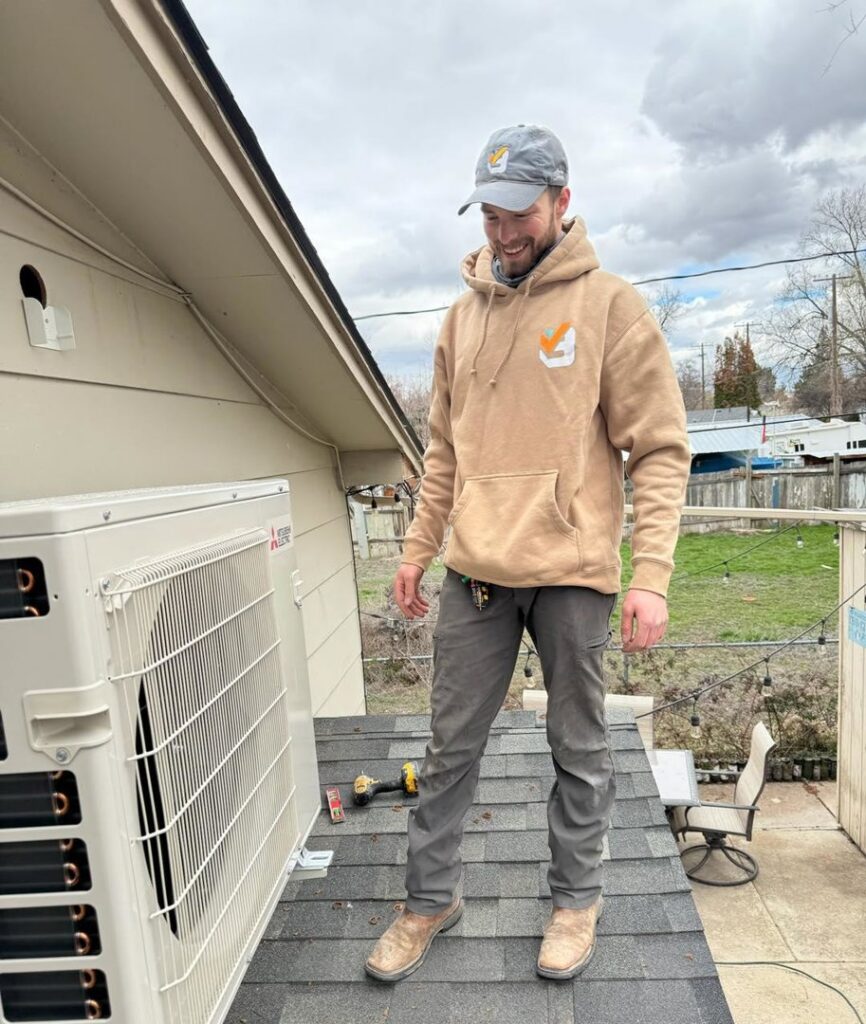 An HVAC technician on a roof next to a mini-split outdoor unit for Boise Valley Heating & Air in Meridian, ID