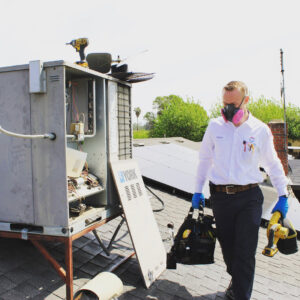 An HVAC technician on a rooftop with tools, ready to service a commercial unit for Controlled Climates Heating and Air Conditioning, Inc. in Fresno, CA.