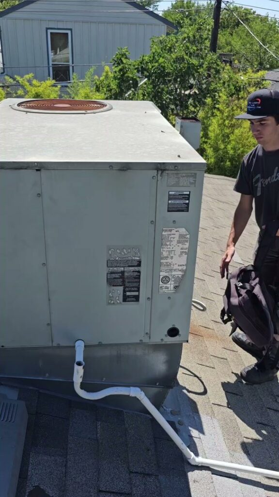 An HVAC technician on a roof next to a large commercial unit, ready to perform service for Ecology Air Innovations in Sacramento, CA.
