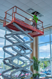 An HVAC technician on a scissor lift installing a new vent for Air-Row Fans in Fortville, IN.