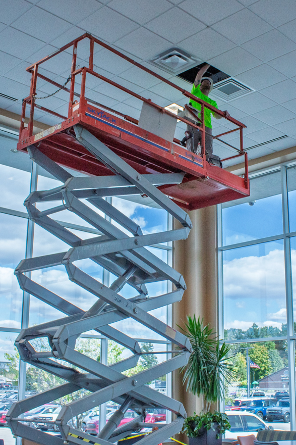 An HVAC technician on a scissor lift installing a new vent for Air-Row Fans in Fortville, IN.