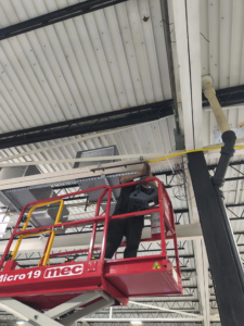 An HVAC technician on a scissor lift working on ceiling ductwork installation for Aaron's Affordable Ac in Indianapolis, IN.