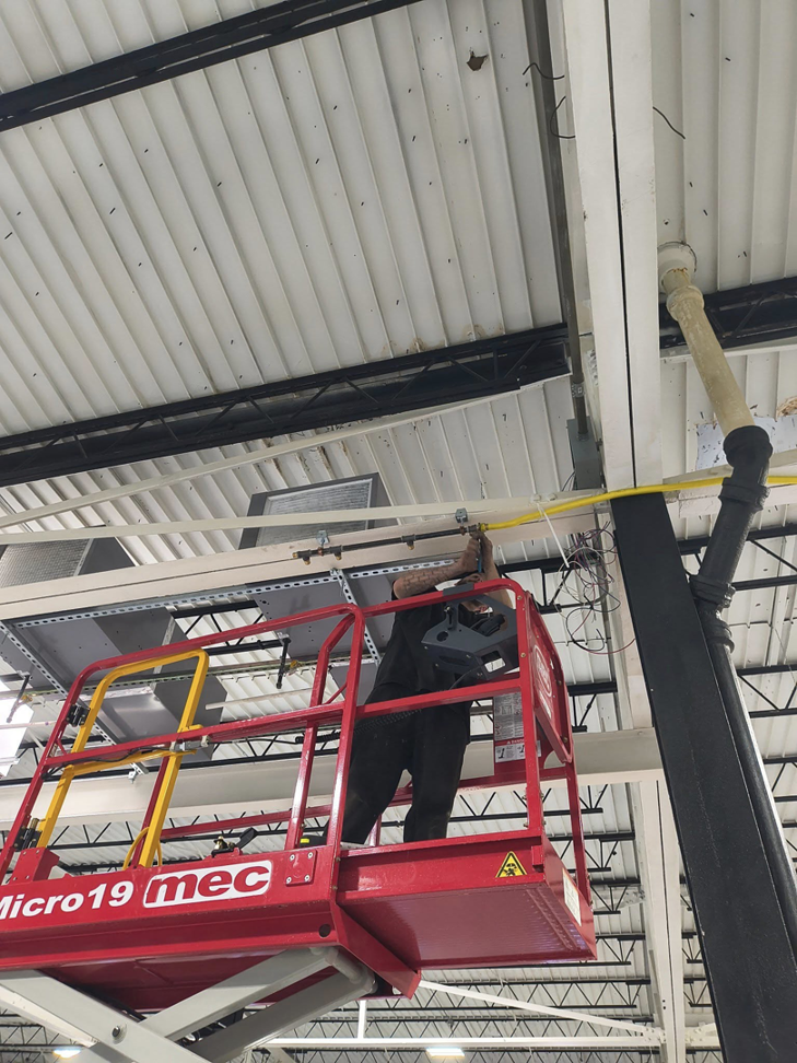 An HVAC technician on a scissor lift working on ceiling ductwork installation for Aaron's Affordable Ac in Indianapolis, IN.
