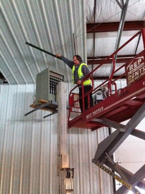 An HVAC technician on a scissor lift working on a large overhead heating unit inside a commercial building for KATS Heating & Cooling in La Grange Park, IL.
