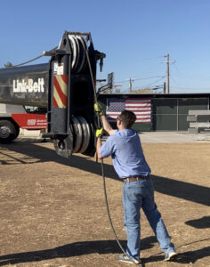 An HVAC technician operating a crane, likely for unit installation, for Advanced Comfort A/C & Heating in Phoenix, AZ.