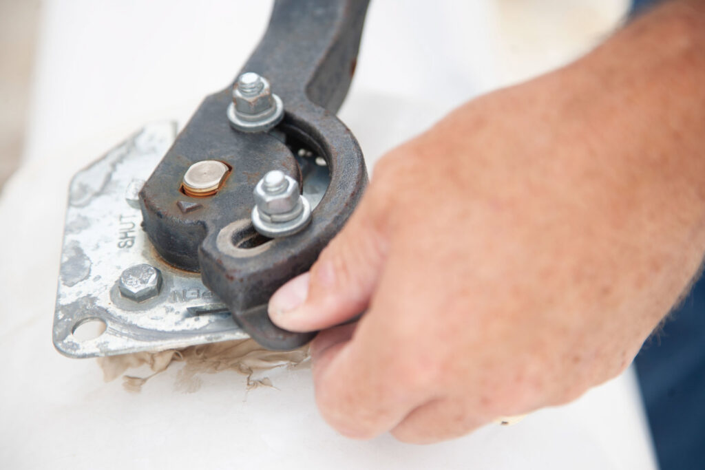A close-up of an HVAC technician operating a tool on a pipe or valve for Climate Systems, Inc. in Sioux Falls, SD.