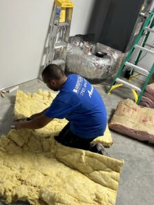An Air Specialty Heating & Air Conditioning technician preparing insulation for an HVAC project in Norfolk, VA.