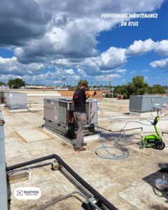 An Empire Tech, Inc. technician performing maintenance by pressure washing a rooftop HVAC unit in Schaumburg, IL.
