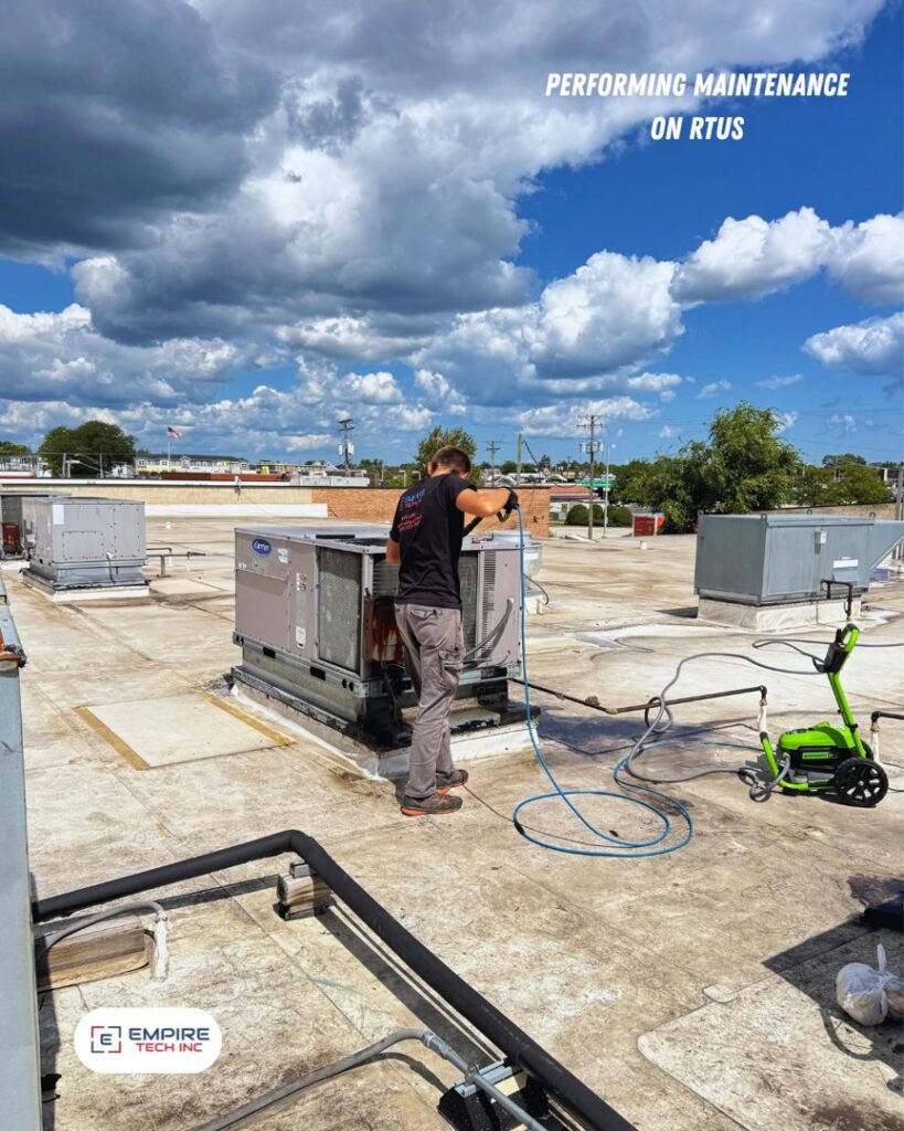 An Empire Tech, Inc. technician performing maintenance by pressure washing a rooftop HVAC unit in Schaumburg, IL.