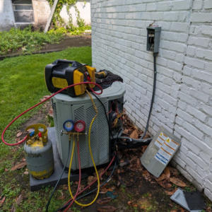 An HVAC technician recharging an outdoor AC unit with refrigerant at Speedy Nelson HVAC Repair in Durham, NC.