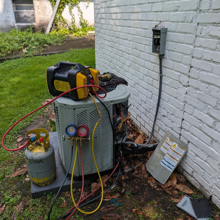 An HVAC technician recharging an outdoor AC unit with refrigerant at Speedy Nelson HVAC Repair in Durham, NC.