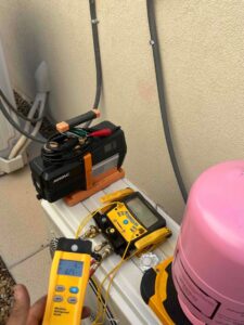 An HVAC technician performing refrigerant service with a manifold gauge and vacuum pump for Sahara Air Conditioning & Heating in Las Vegas, NV