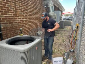 An HVAC technician repairing an outdoor AC condenser unit for Anderson's Air in Newport News, VA