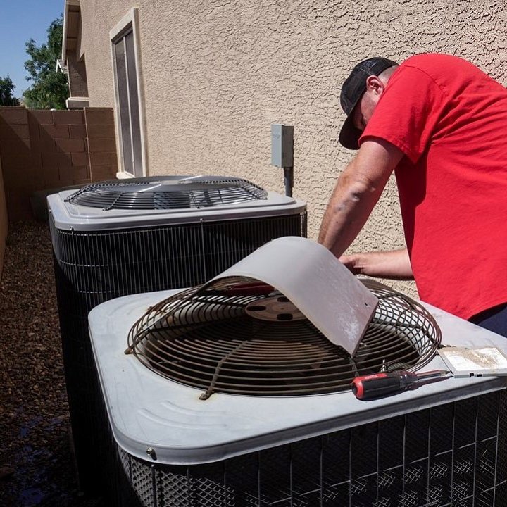An HVAC technician repairing an outdoor AC unit for Diamond AC and Heating in Phoenix, AZ.