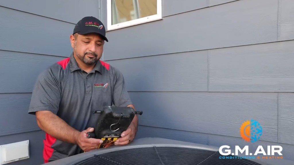 An HVAC technician repairing the internal components of an outdoor AC unit for G.M. AIR Conditioning & Heating in Wichita, KS.