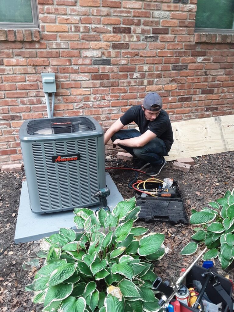 An HVAC technician performing repairs on an outdoor air conditioning unit for Griffin HVAC in Peoria, IL