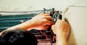 An HVAC technician from Iceman Cooling and Heating repairing the wiring of an indoor AC unit in Baton Rouge, LA.