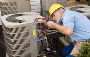 An HVAC technician from Kanawha Valley Maintenance repairing an outdoor air conditioning unit in Charleston, WV