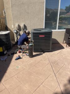 An HVAC technician repairing an outdoor air conditioning unit with tools for MB Heating and Air in Northridge, CA.