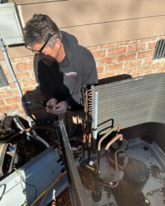 An HVAC technician from Pappy's Heating & Air INC repairing an outdoor AC condenser unit in Clayton, NC.