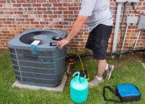 An HVAC technician repairing an outdoor AC unit with a refrigerant tank for Rhode Island HVAC Services in Providence, RI.
