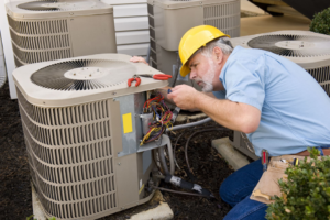 An HVAC technician in a hard hat repairing an outdoor residential air conditioning unit for Service2.0 in Toledo, OH.