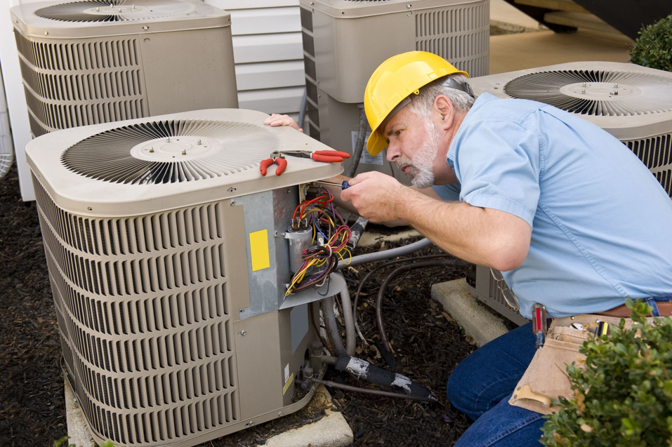 An HVAC technician in a hard hat repairing an outdoor residential air conditioning unit for Service2.0 in Toledo, OH.