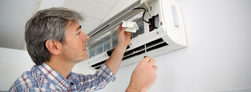 An HVAC technician repairing an indoor split-system AC unit for Signature Plus HVAC, LLC in Toledo, OH.