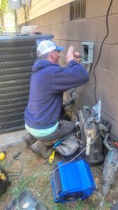 An HVAC technician from Sturdi Home Solutions repairing an outdoor AC unit and electrical connections in Chattanooga, TN.