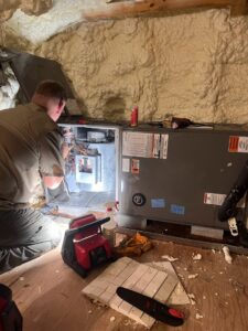 An HVAC technician from Seven Level Services Inc in Cape Coral, FL, repairing an indoor air handler unit in a tight space.