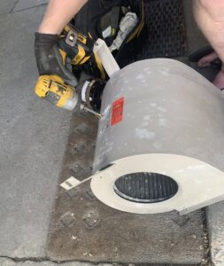 An HVAC technician repairing a blower motor and fan assembly for Peterson Heating & Cooling in Mound City, KS.