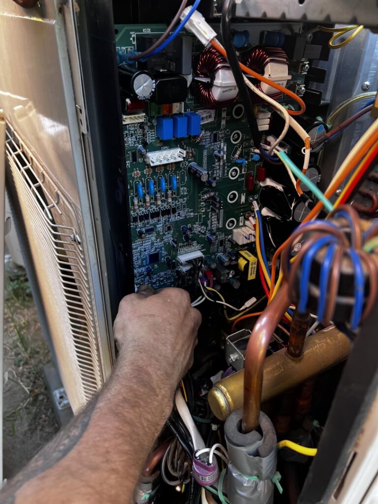 An MB Heating and Air technician repairing the internal circuit board of an HVAC unit in Northridge, CA.